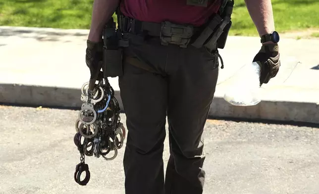FILE - A federal agent holds handcuffs outside immigration court, May 21, 2025, in Phoenix. (AP Photo/Ross D. Franklin, File)