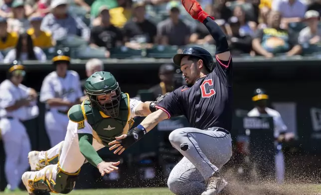 Athletics catcher Willie MacIver (65) attempts to tag out Cleveland Guardians' Steven Kwan (38) during the fifth inning of a baseball game Sunday, June 22, 2025, in West Sacramento, Calif. (AP Photo/Sara Nevis)