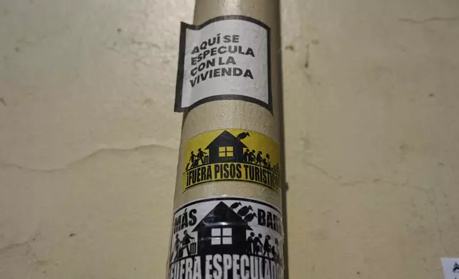 Stickers against tourist holiday rentals are attached on a pipe in downtown Madrid, Spain, Tuesday, June 3, 2025. The writing in Spanish reads: "This is a hotspot for housing speculation," "Tourist rentals out," and "More neighborhood, speculators out." (AP Photo/Manu Fernandez)