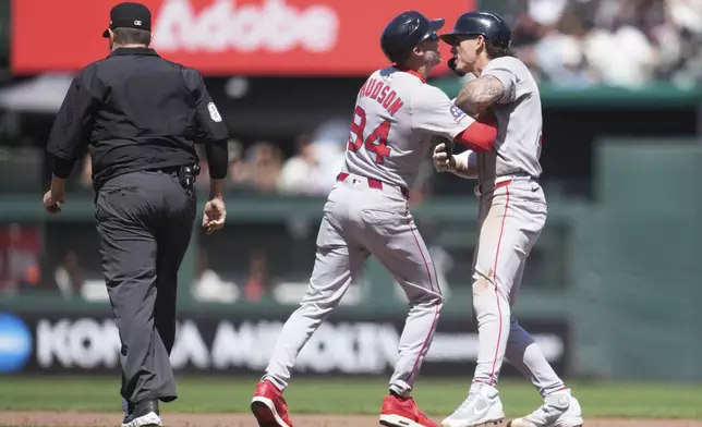 Boston Red Sox' Jarren Duran, right, is held back by third base coach Kyle Hudson (84) while arguing with umpire Doug Eddings, left, during the eighth inning of a baseball game against the San Francisco Giants in San Francisco, Sunday, June 22, 2025. (AP Photo/Jeff Chiu)