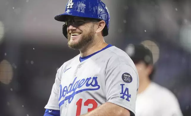 Los Angeles Dodgers' Max Muncy reacts after hitting a pop single to drive in a run as a heavy rain sweeps over Coors Field in the sixth inning of a baseball game against the Colorado Rockies Wednesday, June 25, 2025, in Denver. (AP Photo/David Zalubowski)