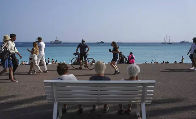 People enjoy the beach as vessels sail during the "Ocean Wonders" themed event in honor of World Oceans Day ahead of the U.N. Ocean Conference on Sunday, June 8, 2025, in Nice, France. (AP Photo/Annika Hammerschlag)