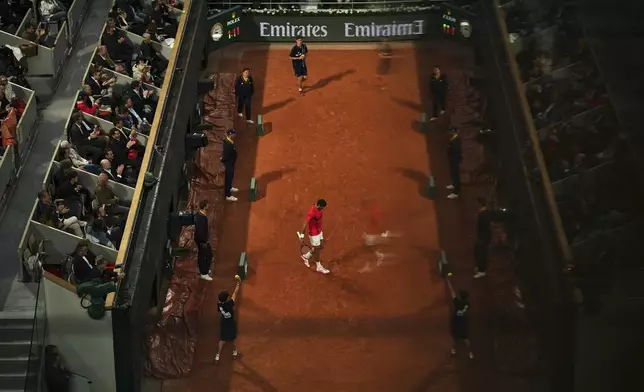 Spectators are reflected in a glass as Serbia's Novak Djokovic prepares to serve against Germany's Alexander Zverev during their quarterfinal match of the French Tennis Open at the Roland-Garros stadium in Paris, Wednesday, June 4, 2025. (AP Photo/Aurelien Morissard)