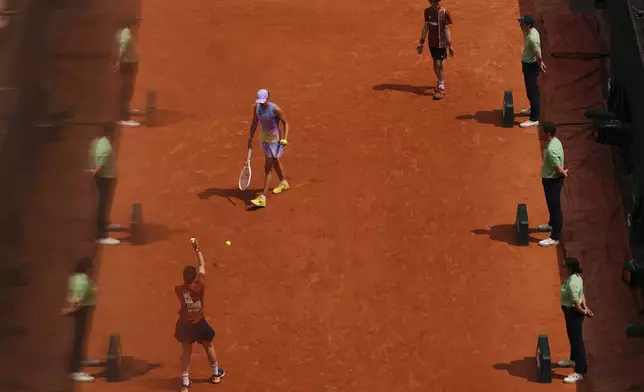Referees are reflected in a glass as Poland's Iga Swiatek prepares to serve Ukraine's Elina Svitolina during their quarterfinal match of the French Tennis Open at the Roland-Garros stadium in Paris, Tuesday, June 3, 2025. (AP Photo/Aurelien Morissard)