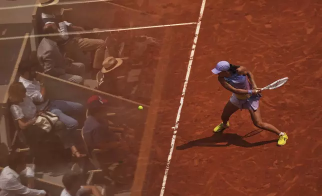 Spectators are reflected in a glass as Poland's Iga Swiatek plays a shot against Ukraine's Elina Svitolina during their quarterfinal match of the French Tennis Open at the Roland-Garros stadium in Paris, Tuesday, June 3, 2025. (AP Photo/Aurelien Morissard)