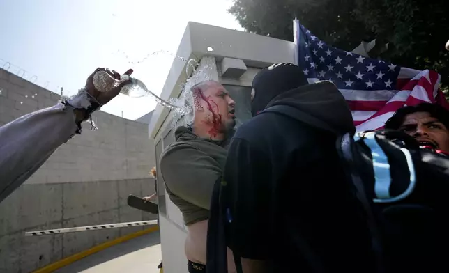 A person who was wearing a MAGA hat, according to witnesses, is confronted by a group of protesters after he was chased down in downtown Los Angeles, Monday, June 9, 2025. (AP Photo/Jae C. Hong)