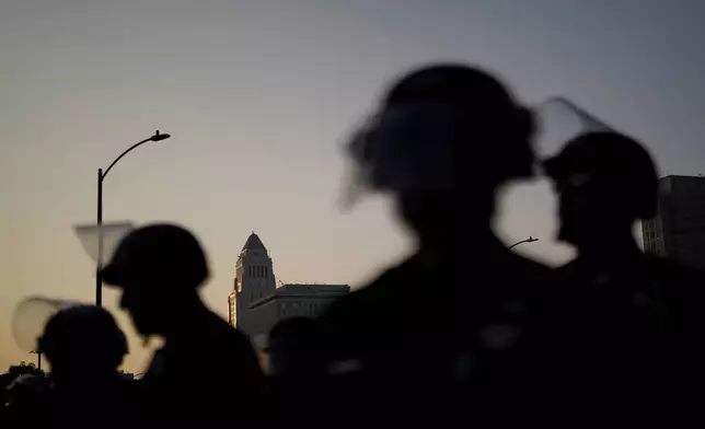 Law enforcement officers in riot gear patrol a street near Los Angeles City Hall in downtown Los Angeles on Monday, June 9, 2025. (AP Photo/Eric Thayer)