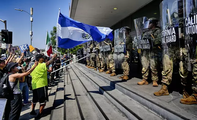 A protester waves a National Flag of El Salvador in front of a line of California National Guard in front of Federal Building on Monday, June 9, 2025, in downtown Los Angeles. (AP Photo/Eric Thayer)