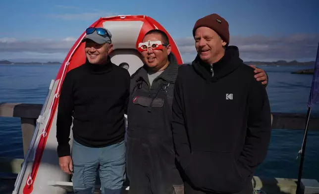 Winners of the annual seal hunting competition posing in front of a dinghy, the competition prize, in Nuuk, Greenland. (AP Photo/Kwiyeon Ha)