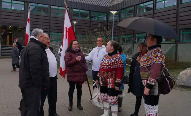 Locals wearing a traditional clothing made of pearl collar and seal hides gather in front of the town hall on the National Day in Nuuk, Greenland. (AP Photo/Kwiyeon Ha)