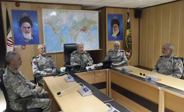In this photo released on Monday, June 23, 2025, by Iranian army press service, Iran's army commander-in-chief Gen. Amir Hatami, center, accompanied by high ranked army commanders, speaks in a video call with top commanders of the army, in Zolfaghar central headquarters, Iran, as portraits of the late revolutionary founder Ayatollah Khomeini, left, and Supreme Leader Ayatollah Ali Khamenei hang on the wall. (Iranian Army Press Service via AP)