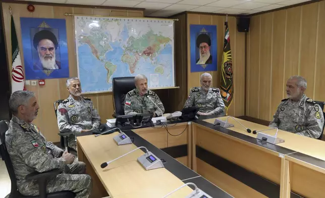 In this photo released on Monday, 23, 2025, by Iranian army press service, Iran's army commander-in-chief Gen. Amir Hatami, center, accompanied by high ranked army commanders, speaks in a video call with top commanders of the army, in Zolfaghar central headquarters, Iran, as portraits of the late revolutionary founder Ayatollah Khomeini, left, and Supreme Leader Ayatollah Ali Khamenei hang on the wall. (Iranian Army Press Service via AP)
