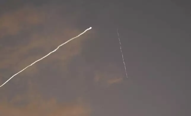 A smoke trail from the Israeli Iron Dome air defense system streaks across the sky as it intercepts missiles launched during an Iranian attack, as seen from Haifa, Israel, early Tuesday, June 24, 2025. (AP Photo/Baz Ratner)