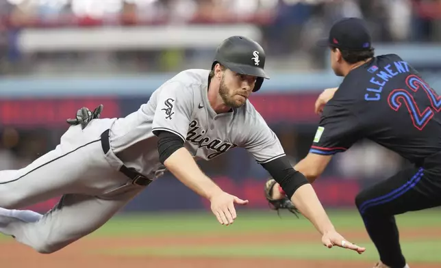 Chicago White Sox's Austin Slater, left, slides into third past Toronto Blue Jays third baseman Ernie Clement (22) during second-inning baseball game action in Toronto, Friday June 20, 2025. (Chris Young/The Canadian Press via AP)