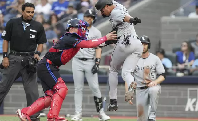 Toronto Blue Jays catcher Tyler Heineman, front left, tags out Chicago White Sox's Josh Rojas, front right, at home plate during second-inning baseball game action in Toronto, Friday June 20, 2025. (Chris Young/The Canadian Press via AP)
