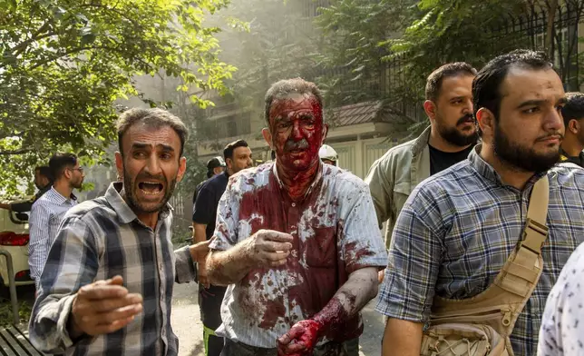 CORRECTS BYLINE.- An injured man is helped to leave the scene after an explosion in downtown Tehran, amid Israel's three-day campaign of strikes against Iran, Sunday, June 15, 2025. (AP Photo/Majid Khahi/ISNA)