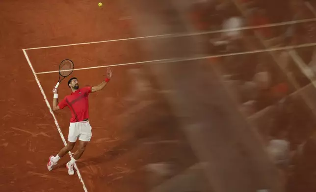 Spectators are reflected in a glass as Serbia's Novak Djokovic plays a shot against Germany's Alexander Zverev during their quarterfinal match of the French Tennis Open at the Roland-Garros stadium in Paris, Wednesday, June 4, 2025. (AP Photo/Aurelien Morissard)
