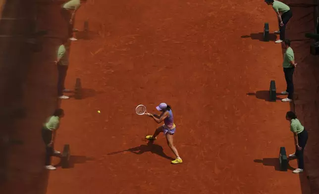 Referees are reflected in a glass as Poland's Iga Swiatek plays a shot against Ukraine's Elina Svitolina during their quarterfinal match of the French Tennis Open at the Roland-Garros stadium in Paris, Tuesday, June 3, 2025. (AP Photo/Aurelien Morissard)