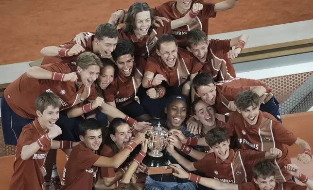 Winner Coco Gauff of the U.S. and ball boys and girls pose with the trophy after the final match of the French Tennis Open against Aryna Sabalenka of Belarus at the Roland-Garros stadium in Paris, Saturday, June 7, 2025. (AP Photo/Christophe Ena)