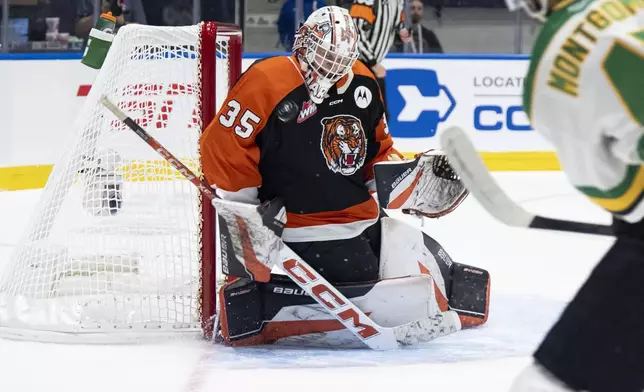 Medicine Hat Tigers goaltender Harrison Meneghin (35) makes a save against London Knights' Blake Montgomery, right, during first-period Memorial Cup final hockey game action in Rimouski, Quebec, Sunday, June 1, 2025. (Christopher Katsarov/The Canadian Press via AP)