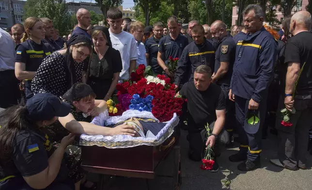 Colleagues and relatives say the last goodbye to firefighters Pavlo Yezhor, Danylo Skadin and Andriy Remenny, killed by Russia's missile attack last week, at the farewell ceremony in front of the fire station in Kyiv, Ukraine, Monday, June 9, 2025. (AP Photo/Efrem Lukatsky)