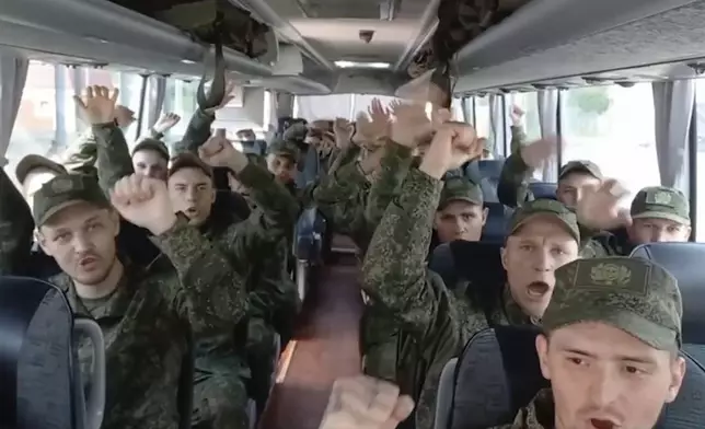 In this photo, taken from video and released by Russian Defense Ministry Press Service on Monday, June 9, 2025, Russian servicemen react in a bus after returning from captivity by a POWs exchange of the first group of servicemen under 25 years of age between Russia and Ukraine, at an undisclosed location in Belarus. (Russian Defense Ministry Press Service via AP)