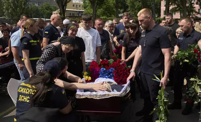 Colleagues and relatives say the last goodbye to firefighters Pavlo Yezhor, Danylo Skadin, and Andriy Remenny, killed by Russia's missile attack last week, at the farewell ceremony in front of the fire station in Kyiv, Ukraine, Monday, June 9, 2025. (AP Photo/Efrem Lukatsky)
