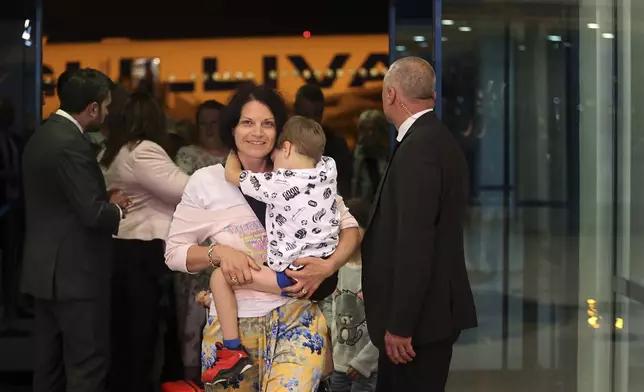 A mother carries her child as the first group of Bulgarian citizens evacuated from Israel, along with dozens of foreign nationals from Slovenia, the U.S., Belgium, Albania, Kosovo and Romania, arrives at Vassil Levsky airport in Sofia, Wednesday, June 18, 2025. (AP Photo/Valentina Petrova)