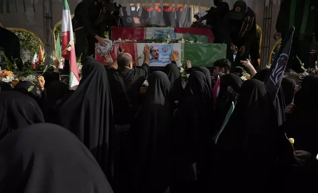 Mourners try to touch the flag-draped coffins during the funeral ceremony of the Iranian armed forces generals, nuclear scientists and their family members who were killed in Israeli strikes, at Enqelab-e-Eslami (Islamic Revolution) square, in Tehran, Iran, Saturday, June 28, 2025. (AP Photo/Vahid Salemi)