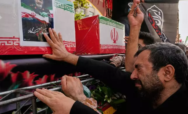 A mourner touches the flag-draped coffin of Revolutionary Guard chief Gen. Hossein Salami, during the funeral ceremony of the Iranian armed forces generals, nuclear scientists and their family members who were killed in Israeli strikes, at Enqelab-e-Eslami (Islamic Revolution) square, in Tehran, Iran, Saturday, June 28, 2025. (AP Photo/Vahid Salemi)