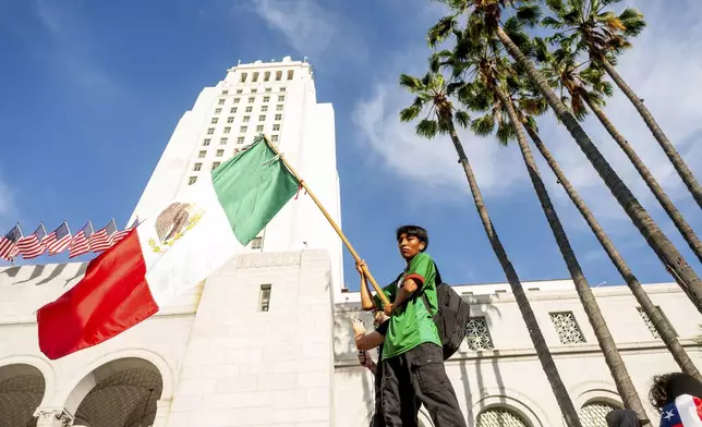 Alberto Gonzalez waves a Mexican flag outside city hall while demonstrating against U.S. Immigration &amp; Customs Enforcement raids on Friday, June 13, 2025, in Los Angeles. (AP Photo/Noah Berger)