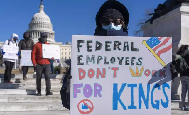 FILE - A federal employee, who asked not to use their name for fears over losing their job, protests with a sign saying "Federal Employees Don't Work for Kings" during the "No Kings Day" protest on Presidents Day , Feb. 17, 2025, near the Capitol in Washington. (AP Photo/Jacquelyn Martin, File)