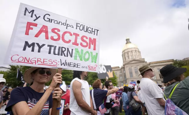 A demonstrator holds a sign during a "No Kings" protest, Saturday, June 14, 2025, in Atlanta. (AP Photo/Mike Stewart)