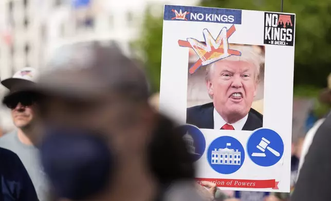 A demonstrator holds a sign during a "No Kings" protest, Saturday, June 14, 2025, in Atlanta. (AP Photo/Mike Stewart)