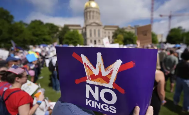A demonstrator holds a sign during a "No Kings" protest, Saturday, June 14, 2025, in Atlanta. (AP Photo/Mike Stewart)