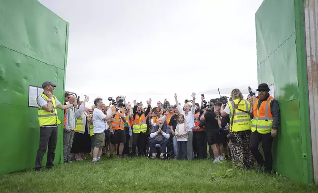 Emily Eavis, center right, and Michael Eavis, center, react with others as the gates open, on the first day of the Glastonbury Festival at Worthy Farm, in Somerset. England, Wednesday June 25, 2025. (Yui Mok/PA via AP)