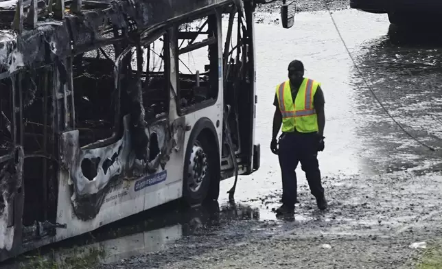 An official walks past the burnt wreckage of a bus at Southeastern Pennsylvania Transportation Authority facility in Philadelphia, Thursday, June 5, 2025. (AP Photo/Matt Rourke)