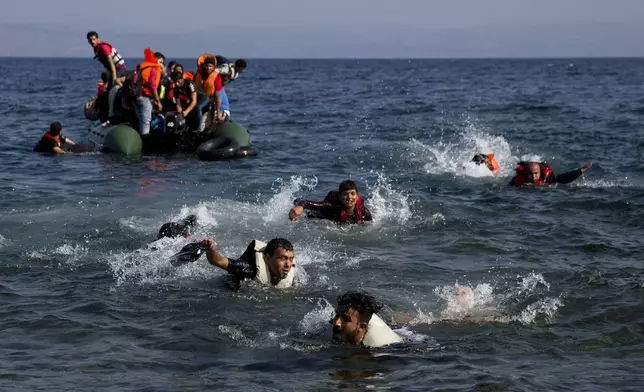FILE - Migrants, whose boat stalled while crossing from Turkey to Greece, swim to the island of Lesbos, Greece, on Sept. 20, 2015. (AP Photo/Petros Giannakouris, File)