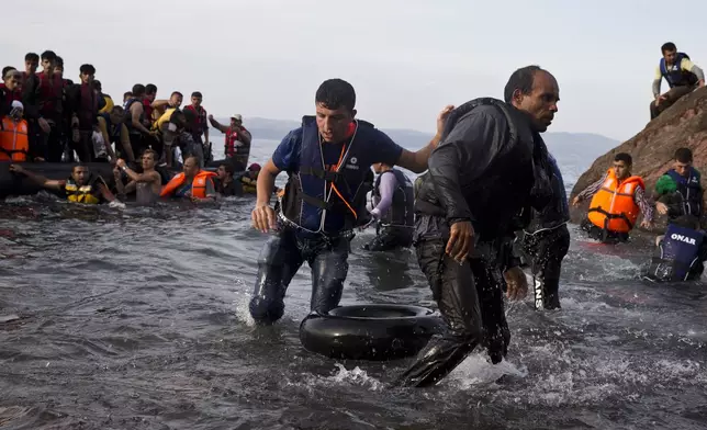 FILE - Migrants and refugees arrive on a dinghy after crossing from Turkey to Lesbos island, Greece, Sept. 9, 2015. (AP Photo/Petros Giannakouris, File)