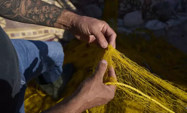 Fisherman Stratos Valamios untangles the nets at the village of Skala Sikamias, on the Greek island of Lesbos, Thursday, May 15, 2025. (AP Photo/Petros Giannakouris)