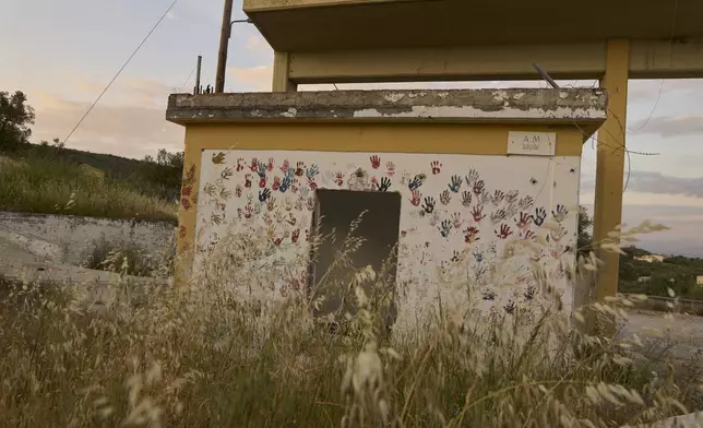 Colorful handprints are seen on the wall of a small structure in the remains of the former Moria refugee camp, which was destroyed by a massive fire in September 2020, on the island of Lesbos, Greece, Monday, May 12, 2025. (AP Photo/Petros Giannakouris)