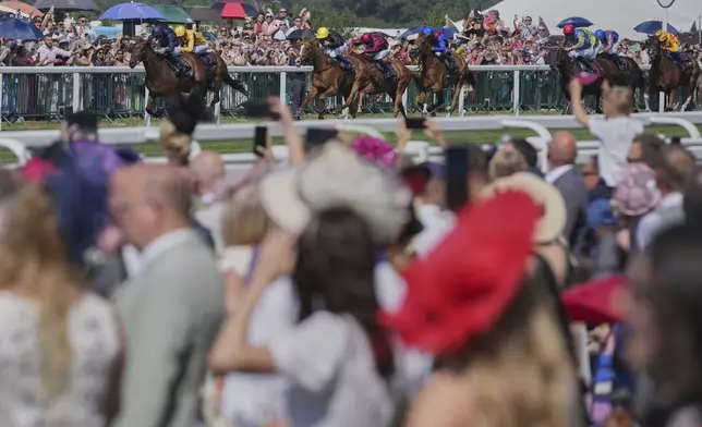 Crowds cheers on the horses running in the Ribblesdale Stakes on the third day of the Royal Ascot horse race meeting, traditionally called Ladies Day, at Ascot, England, Thursday, June 19, 2025. (AP Photo/Kin Cheung)