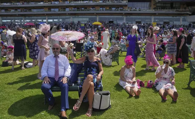 Racegoers relax in the sunshine between races as temperatures rise to over 30c (86f), on the third day of the Royal Ascot horse race meeting, traditionally called Ladies Day, at Ascot, England, Thursday, June 19, 2025. (AP Photo/Kin Cheung)
