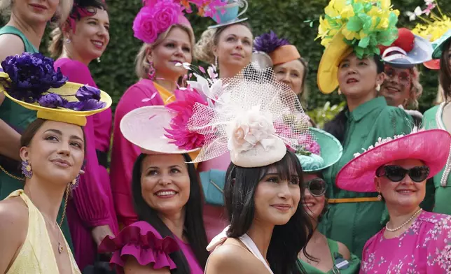 Racegoers wearing colorful outfits pose for photographs as they arrive on the first day of the Royal Ascot horse race meeting at Ascot, England, Tuesday, June 17, 2025. (AP Photo/Alberto Pezzali)