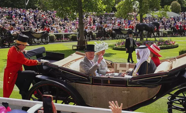 Britain's King Charles, left, with Queen Camilla waves to the crowd as he arrives with Prince Faisal bin Salman Al Saud, second right, in the Parade Ring on the first day of the Royal Ascot horse race meeting at Ascot, England, Tuesday, June 17, 2025. (AP Photo/Alberto Pezzali)