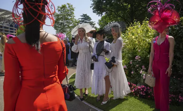 Racegoers pose for photographs wearing ornate hats on the third day of the Royal Ascot horse race meeting, traditionally called Ladies Day, at Ascot, England, Thursday, June 19, 2025. (AP Photo/kKn Cheung)