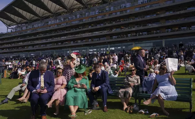 Racegoers enjoy the warm weather as they watch the racing on the first day of the Royal Ascot horse race meeting at Ascot, England, Tuesday, June 17, 2025. (AP Photo/Alberto Pezzali)