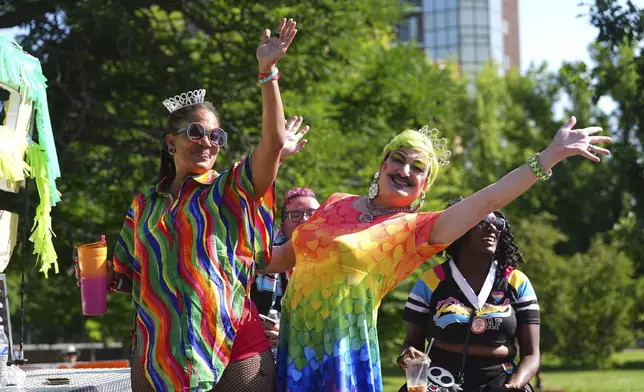 Participants wave as they ride on a float during a parade to celebrate pride month Sunday, June 29, 2025, in Denver. (AP Photo/David Zalubowski)