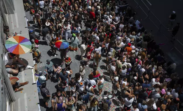 Revelers crowd the sidewalk and peer from windowsills during the Pride March on Sunday, June 29, 2025, in New York. (AP Photo/Olga Fedorova)