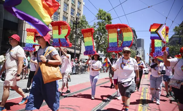 FILE - Revelers walk along Market Street during a Pride Parade, June 30, 2024, in San Francisco. (AP Photo/Ethan Swope, File)